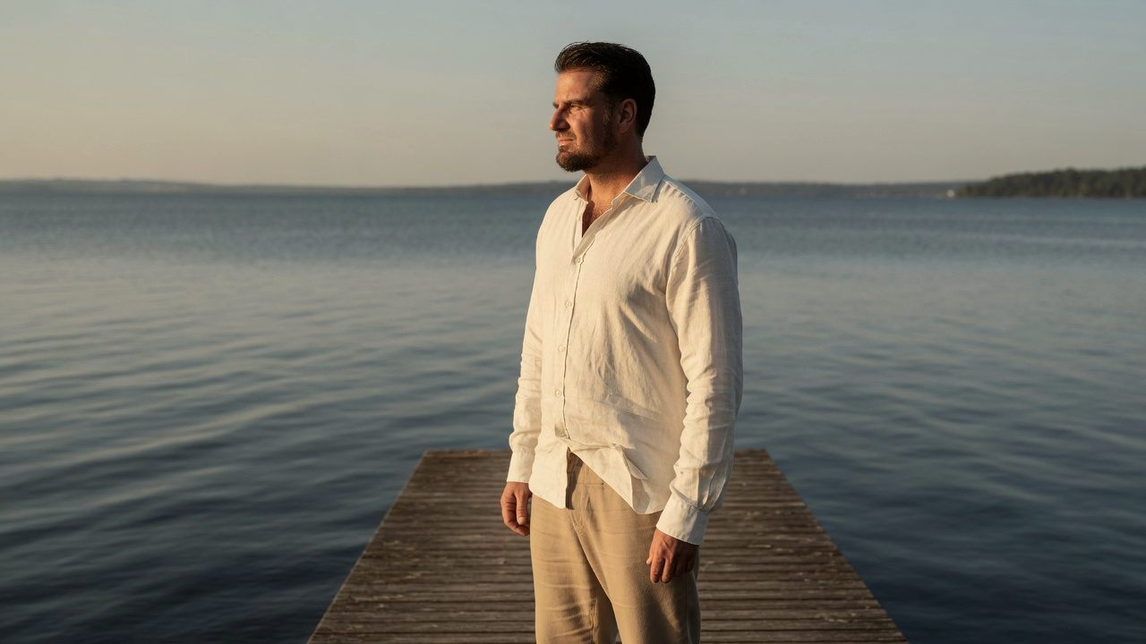 Andreas Ehstand steht ruhig auf einem Steg am See