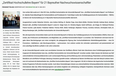 Gruppenfoto von Fachleuten bei einer Konferenz, lächelnd und stehend in einem Raum.